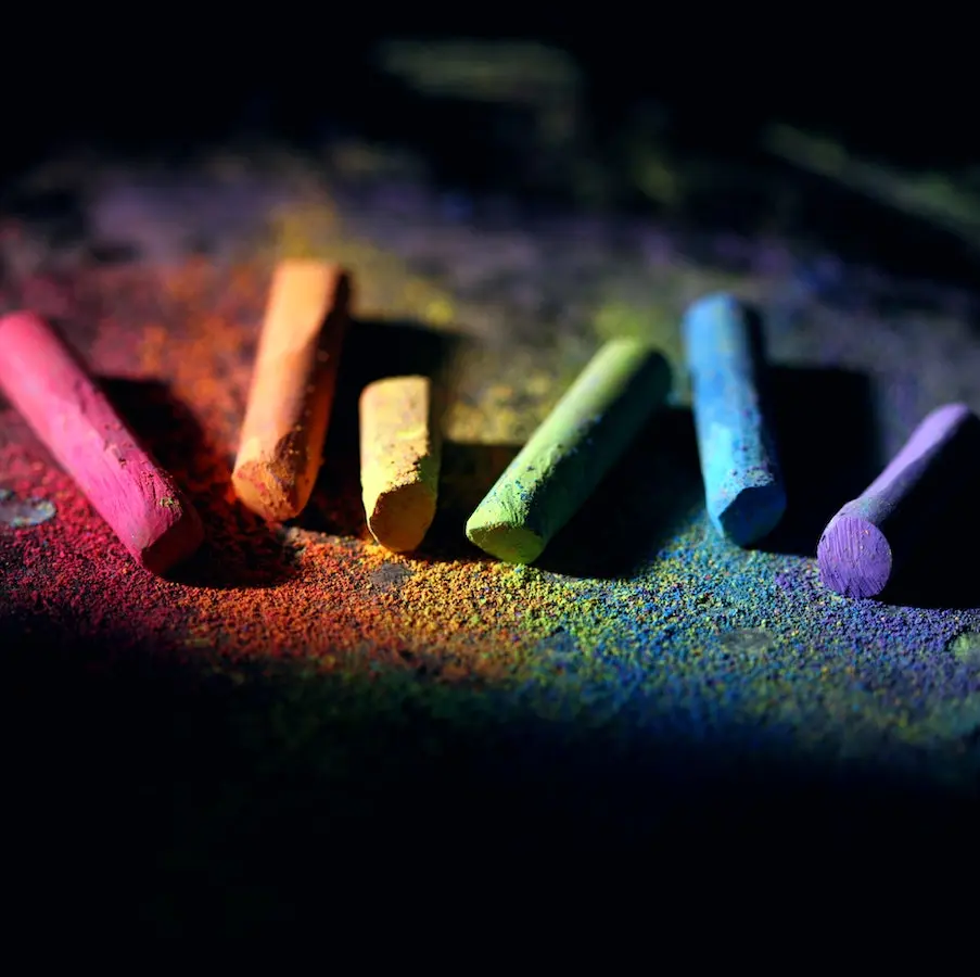 Multi colored pieces of chalk on color dusted surface